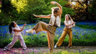 3 dancers performing outside in a woodland setting