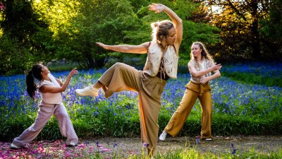 3 dancers performing outside in a woodland setting