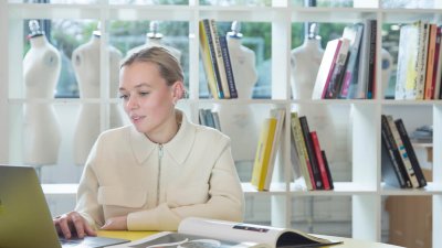 Student working at laptop in front of bookcase