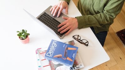 Person sat at laptop working with design book