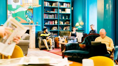 A group of students seated on sofas in a blue room with book cases and art on walls