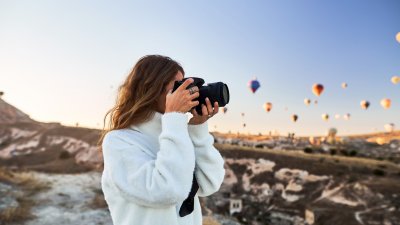 A student taking a photo standing underneath a sky full of hot air balloons