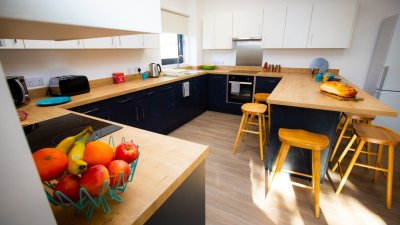 A student kitchen equipped with toaster, kettle, microwave, table, chairs and an oven