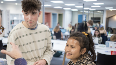 Two students speaking a staff member in The Compass