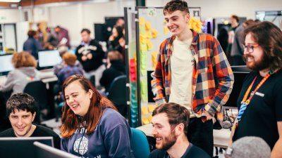 A group of games students smiling and laughing around a computer