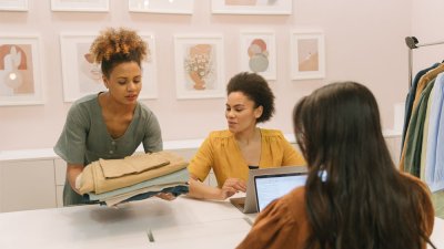 Three Sustainable Fashion students looking at fabric