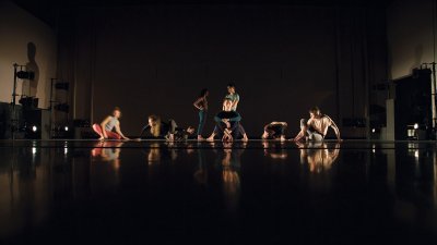 Students holding still in dancing positions on a dark stage