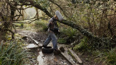 A person walking in a woodland with a large microphone