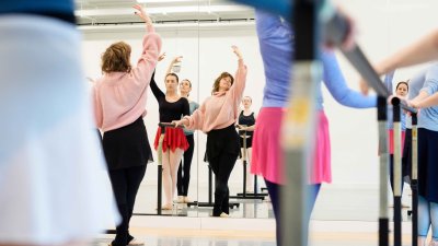 An adult ballet class posing in a studio looking at mirrors