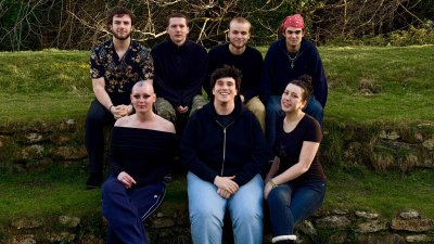 A group of people sat on steps covered in grass