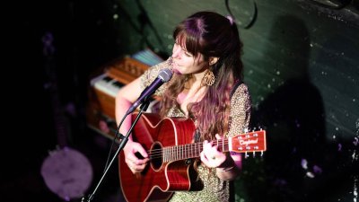 A musical performing with a guitar and singing into a microphone