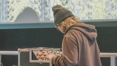 A young person stood at a audio mixing desk