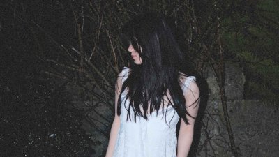 A person in a white dress against a very dark external background