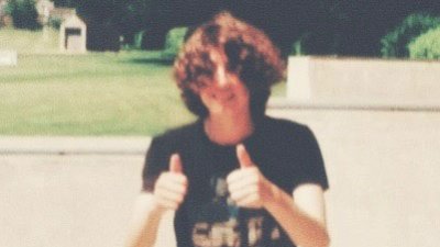 A photo of a person looking at the camera with both of their thumbs up