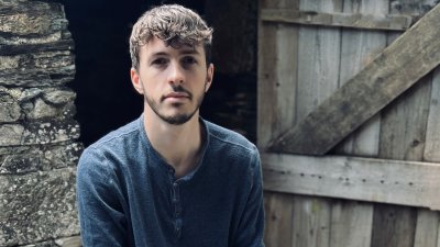 A person sat outside in front of a wooden barn door