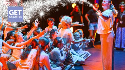 A group of young performers on the Hall for Cornwall Stage with a winter motif on the image