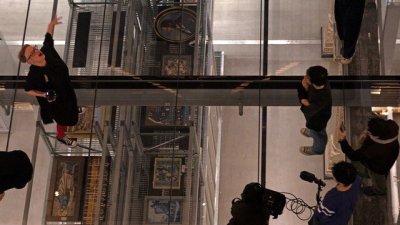 A Birdseye view looking down on performers on a glass floor above a museum gallery
