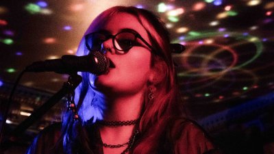 Music artist Jolie Lane stood a microphone in dim stage lighting