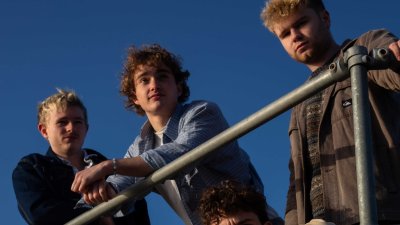 A group of 4 leaning against a metal bar with blue sky in the background