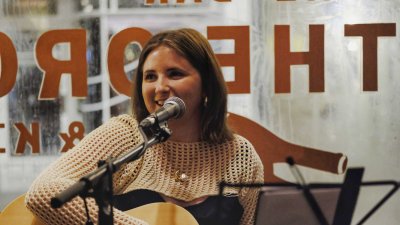 A performer playing the guitar and singing into a microphone