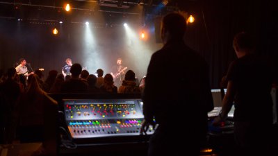 A silhouet image of a person mixing a live band in a gig studio