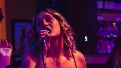 Singer, Rosie May Jones, performing on stage and signing into a microphone