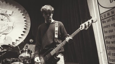A black and white photo a someone performing on stage playing the bass guitar