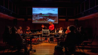 Gr group of musicians at various stations in a circle interacting and performing electronic music