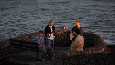 A group of musicians outside with a sea in the background