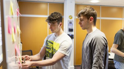 Two students mind mapping with post it notes on a white board