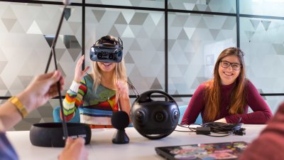 Two Falmouth University students at a table, one wearing a VR headset