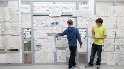 Students standing at a wall full of ideas written on paper