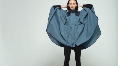 Model wearing cape design with hands behind head