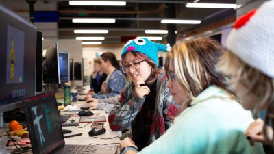 Three Falmouth University students around a computer at the 2025 Games Jam