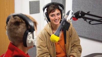 Students with headphones laughing and speaking into microphone