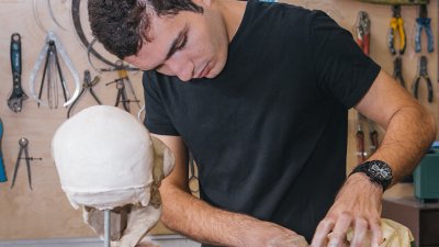Individual working in a workshop to make a mask