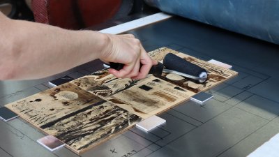 Someone inking a wood cut for mokulito