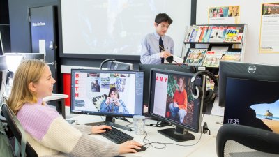 a male and female student in an IT suite with magazines on a shelf