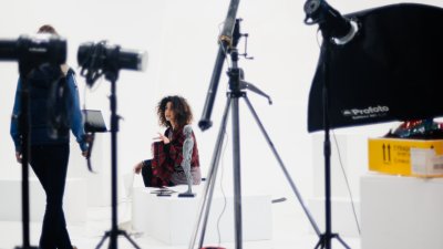 Photography studio with figure surrounded by cameras and lighting