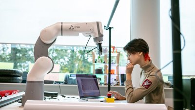 Robotics student seated with a laptop and robotics arm