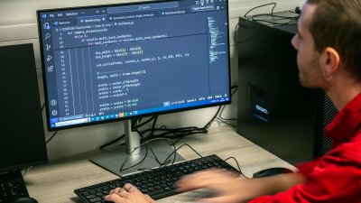 A Falmouth University student writing code on a desktop computer