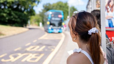 A female student waiting at the bus stop with a bus approaching