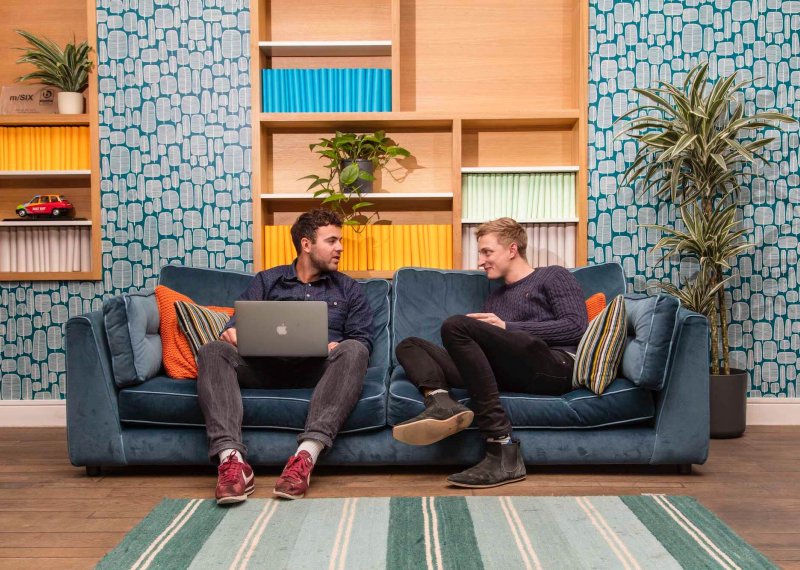 Falmouth advertising alumni Ben Fallows and Matt Deacon chatting on a sofa.