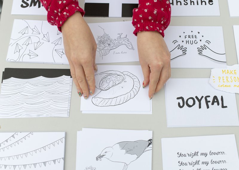 Two hands with red sleeves on a table with drawings