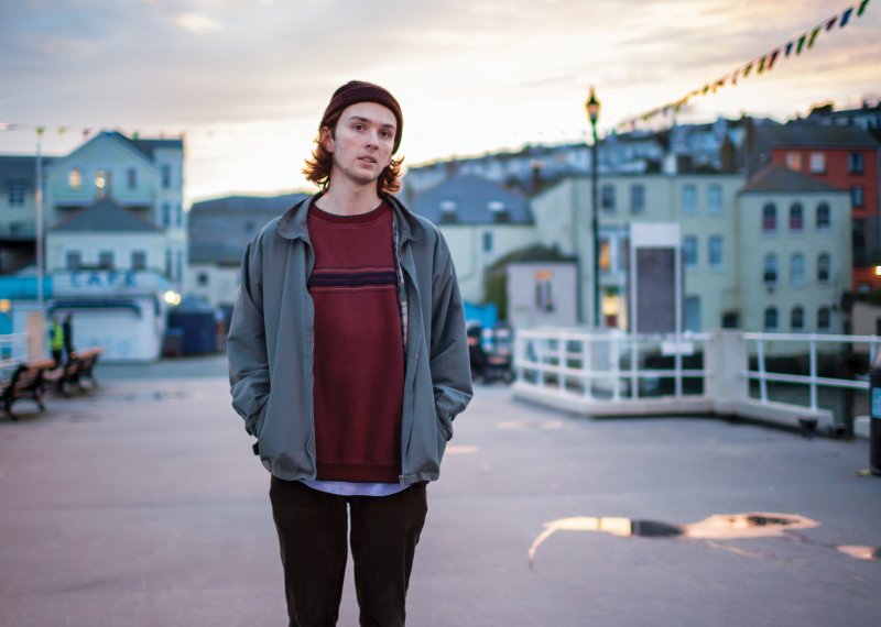 Student on pier in Falmouth with skateboard.