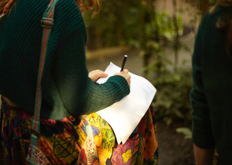 A girl in a green jumper writing on white paper