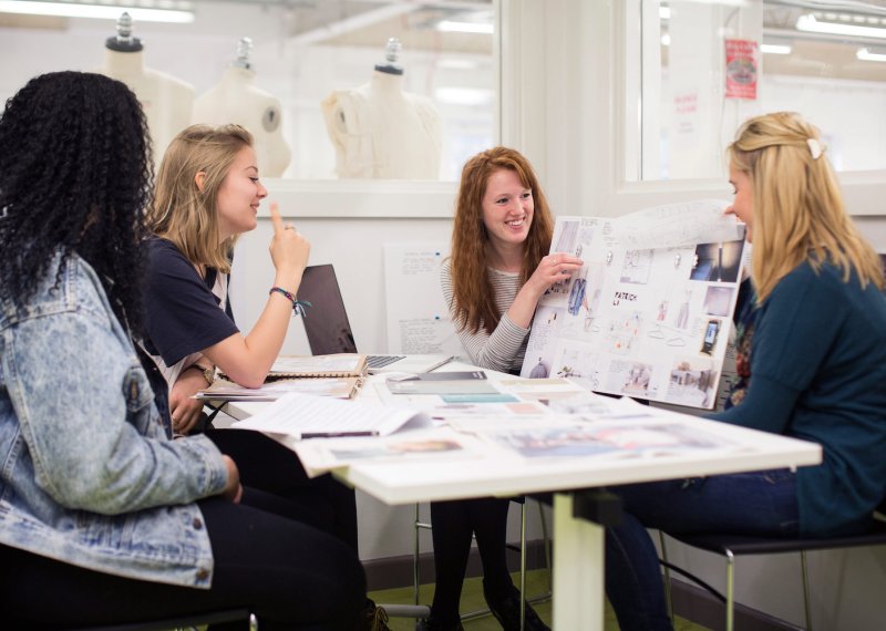 Falmouth University students discussing work on boards in a studio.