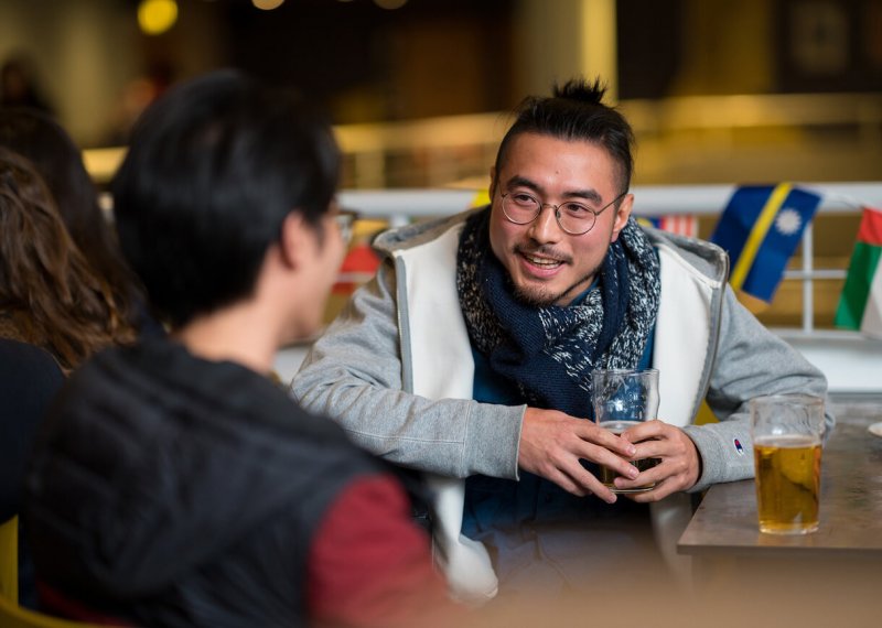 Students chatting to each other with a beer in hand.