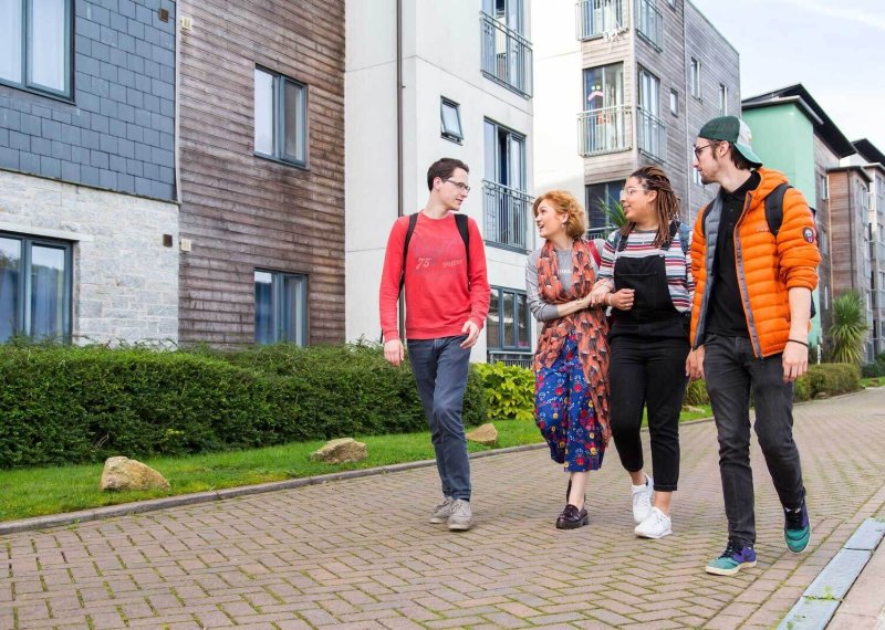 Students walking through Glasney Village with arms linked.