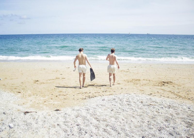 Two Falmouth University students walking on the sand towards to sea